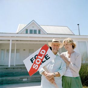 people standing in front of a house with a sold sign