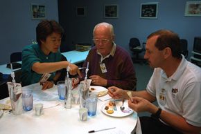 Payload specialists Chiaki Mukai and Sen. John Glenn and mission commander Curtis L. Brown Jr. sample space foods.
