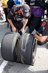 Crew members check the tire wear after a pit stop during a NASCAR Sprint Cup Series race.