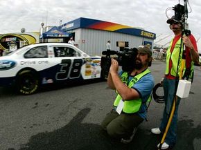 ESPN film crew members capture David Gilliland, driver of the #38 Ford Drive One Ford, leaving the garage area at the beginning of practice for the NASCAR Sprint Cup Series Sylvania 300 at New Hampshire Motor Speedway on Sept. 13, 2008 in Loudon, N.H.