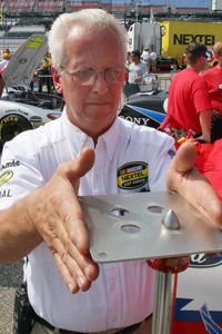 NASCAR official George Metrick examines a restrictor plate during a pre-race inspection for qualifying.