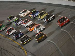 NASCAR race cars running three-wide through a turn at Daytona