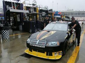 Crew members at Nextel Sprint Cup Series Bank of America 400 push car out of garage area after rain delay cancels qualifying and practice.  