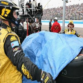 Crew members cover up tires during NASCAR rain delay. 