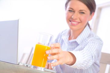Young woman reaching for glass of orange juice