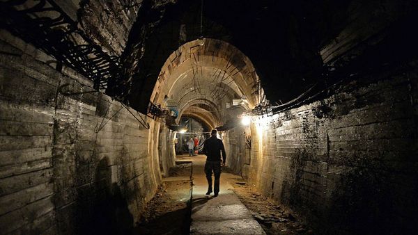 Men walking through dark underground architecture.