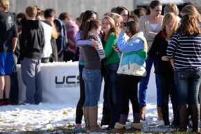 2013年12月13日，科罗拉多州阿拉帕霍高中发现枪手后，学生们站在足球场上互相安慰。＂border=
