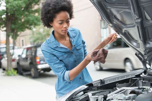 A woman checking the oil of her car.