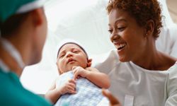 A mother accepts her new baby from the delivery doctor.