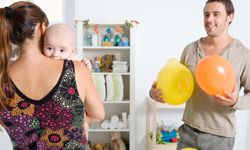 A mother and a father with a newborn baby and party decorations in a nursery.