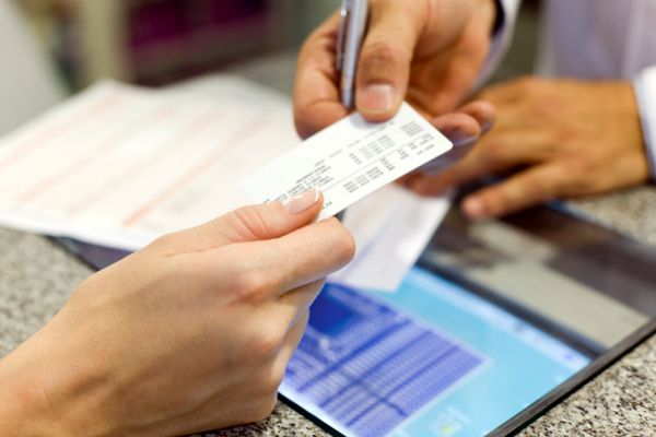 A patient hands an insurance card to someone at a doctor's office.