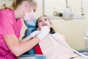 dental hygenist cleaning patient's teeth