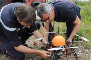 两名法国消防队员在兰德斯森林地区的测试中准备一架无人机。＂border=