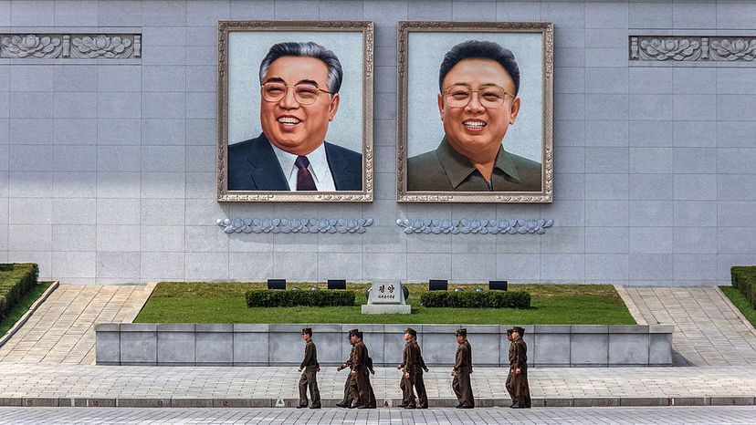 士兵走在前面的巨幅肖像金日成(左)和金正日在金日成广场上,平壤,朝鲜。Cappronnier Benoit /盖蒂图片社”border=