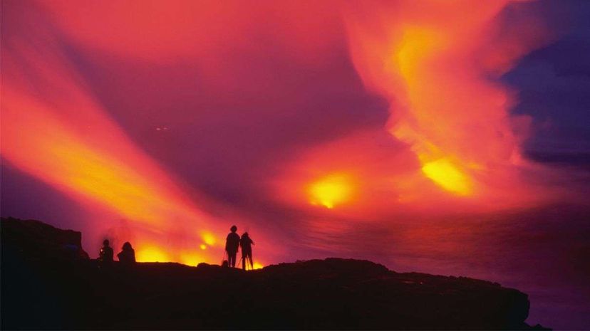 当天空变成火红的粉色和紫色时，游客们观看着夏威夷火山国家公园内基拉韦厄火山喷发时流入海洋的熔岩。Douglas Peebles/Corbis by Getty Images＂width=