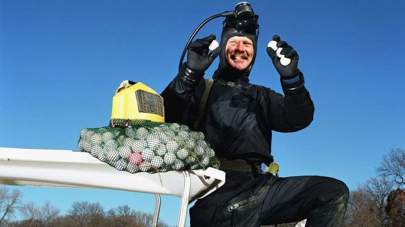 A golf ball diver hold up his hard-earned loot. Andrew Geiger/Getty