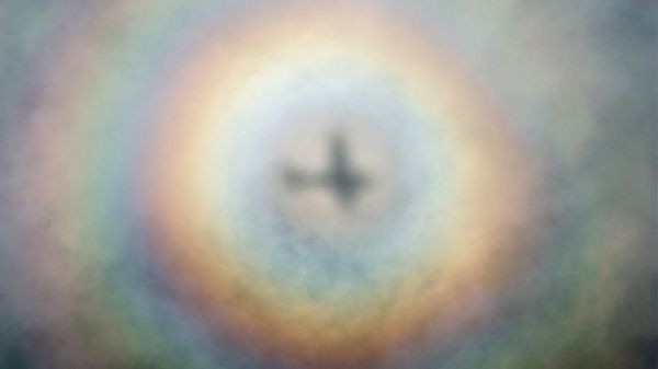 circular rainbow around airplane shadow on clouds