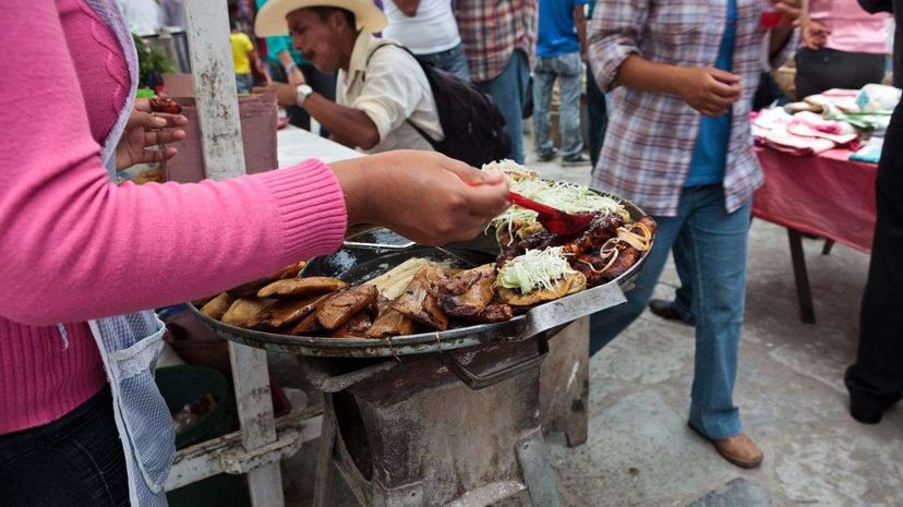 一名妇女准备墨西哥街头食品：痣辣酱玉米饼，炸玉米饼，炸玉米饼和墨西哥玉米饼。Jacobo Zanella/Getty图像“width=