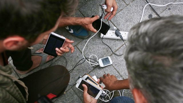 Migrants recharge their phones