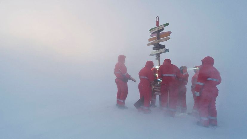 在一年中最短的一天，也被称为仲冬，极地研究人员在暴风雪期间越过路标。对于许多南极研究人员来说，在冬至上张贴街头标志是一种传统。Stefan Christmann/Getty Images“width=