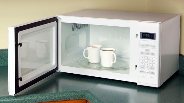 coffee cups sitting in open microwave oven