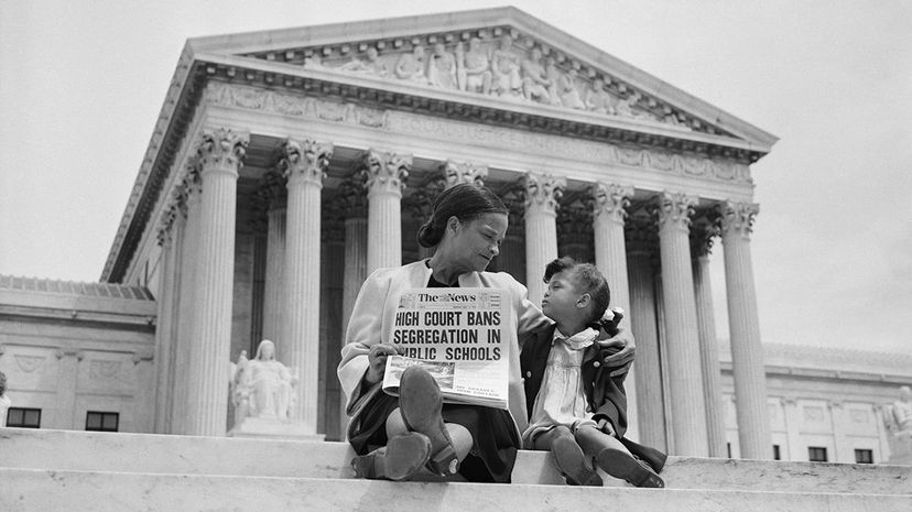 Nettie Hunt sits on the steps of the U.S. Supreme Court with her daughter Nickie, holding a newspaper declaring the Brown v. Board decision to overturn segregation in schools. Bettmann /Getty Images