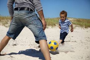 boy kicking ball on beach