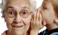 little boy whispering into older woman's ear