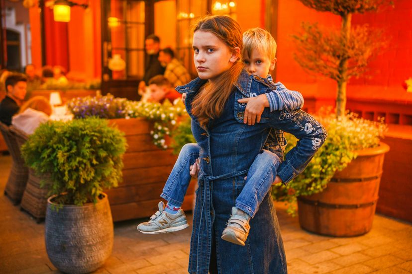 Older sister holding her brother on her back in market