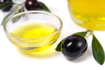 Olive oil, black olives, olive branches and a bottle of olive oil.
