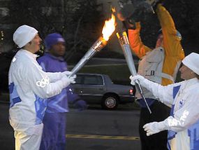 Torchbearer Stephanie Stockman, an employee in the NASA Laboratory for Terrestrial Physics in Maryland, passes the flame to the next runner.