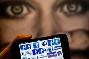 A man holds a smartphone displaying Facebook logo in front of a poster at the International Cyberbullying Congress in Berlin, Germany, in 2013.