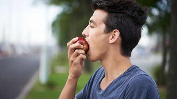 a young man taking a bite of an apple