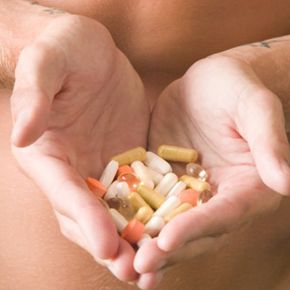 hands holding assortment of vitamins and pills