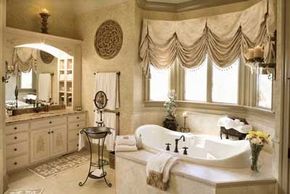 An elegant bathroom featuring gold accents, a large soaking tub, and custom windows.&nbsp;