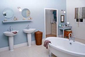A bathroom with baby blue walls, two matching sinks and a pedestal tub.&nbsp;