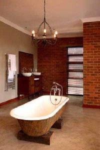 An open concept bathroom featuring a large soaker tub beneath a chandelier.&nbsp;