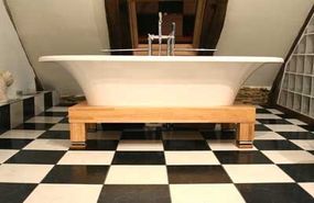 A large soaker tub accented by checkered tiles and odd-shaped walls.&nbsp;