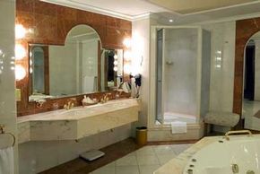 A luxurious bathroom with white stone countertops, a whirlpool tub, and a corner shower.&nbsp;