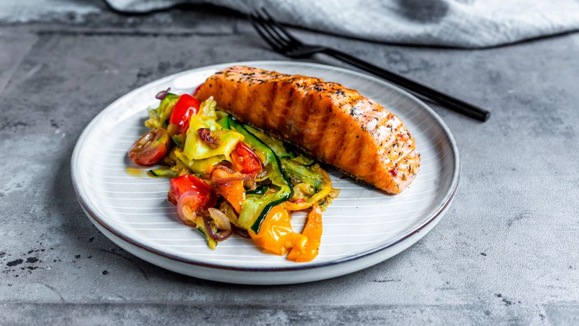 A plate with salmon and some vegetables.