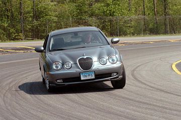 A vehicle test driver drives a Jaguar sedan around the company's test track in East Haddam, Conn.