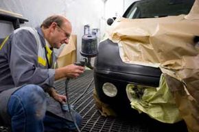 Man in shop painting black car