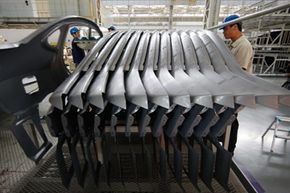 Workers at a Hyundai car factory line up pressed metal parts used in its car assembly line in Beijing, China.