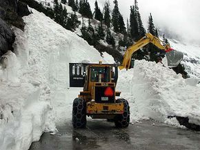 A bulldozer clears avalanche debris from a road in Glacier National Park.