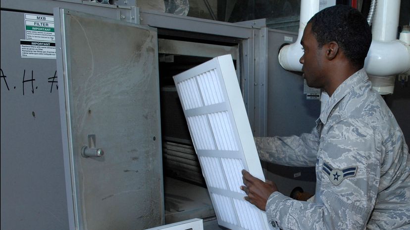 Airman replacing an air conditioning filter.