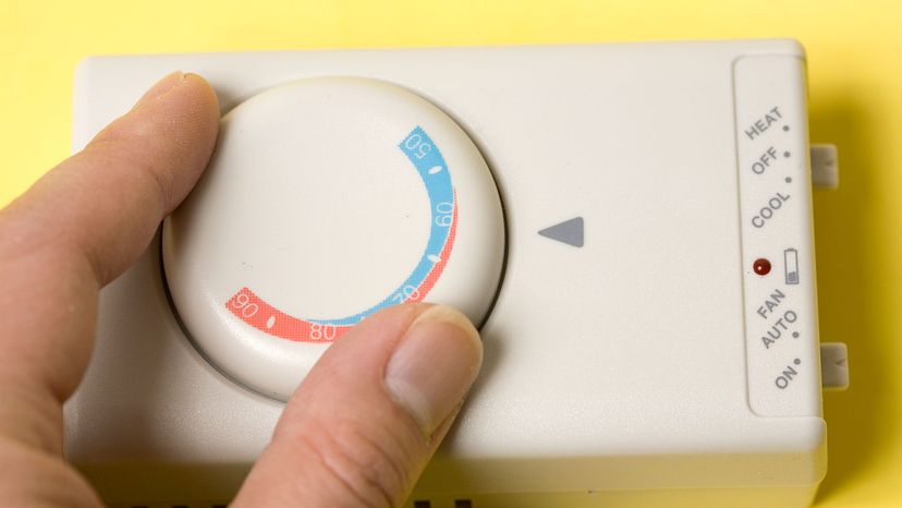 Fingers turn the&nbsp;dial on a thermostat.