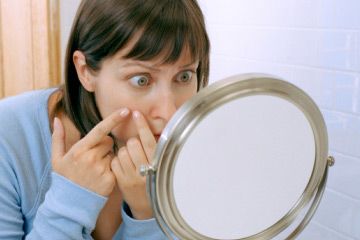 Woman poking face in mirror