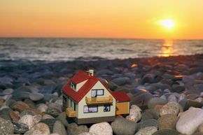 Model house on rocky beach at sunset