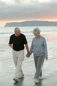 senior couple walk on the beach hand-in-hand