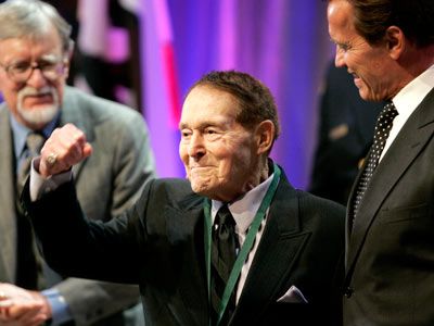 Jack LaLanne pumps his fist after being inducted into the California Hall of Fame. California Governor Arnold Schwarzenegger is to his right.